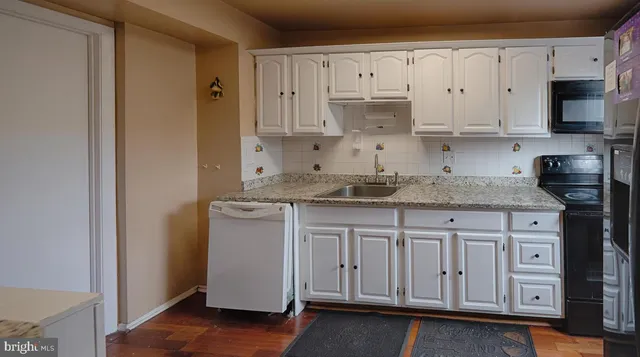 a kitchen with granite countertop white cabinets stainless steel appliances and sink