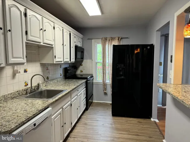 a kitchen with granite countertop a refrigerator and a sink