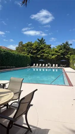 a view of swimming pool with seating area and trees in the background