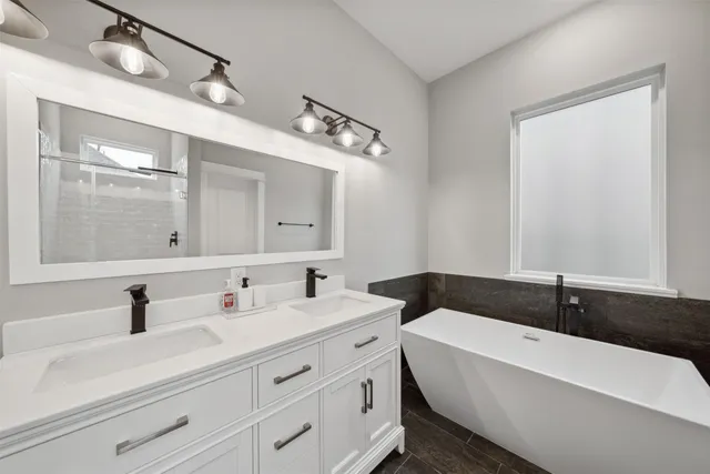 a bathroom with a bathtub a double vanity sink and mirror