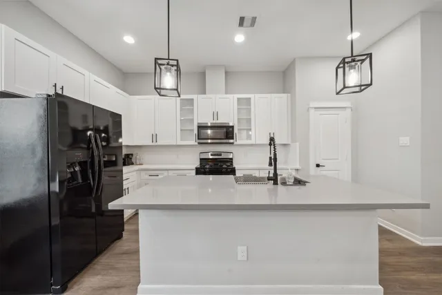 a kitchen with kitchen island a counter space a refrigerator and cabinets