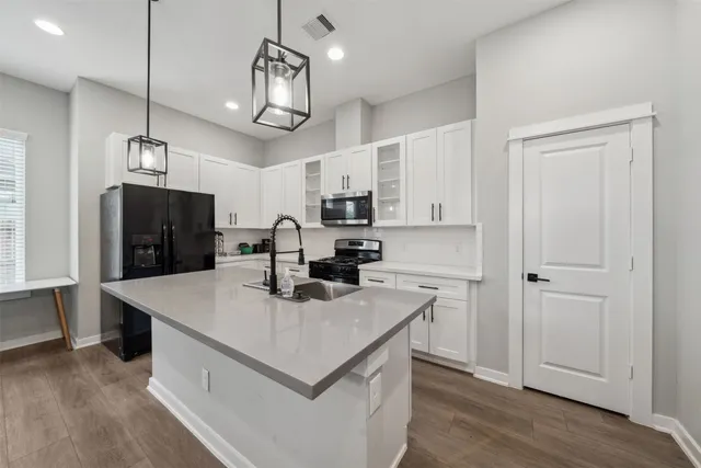 a kitchen with kitchen island a counter space a sink appliances and cabinets