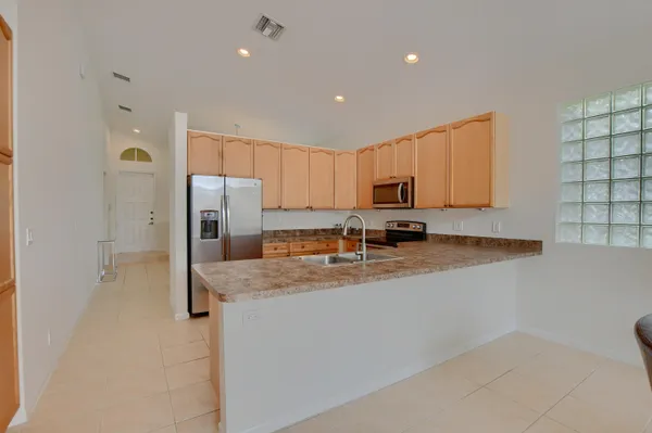 a kitchen with stainless steel appliances granite countertop a refrigerator a stove a sink a microwave a oven and white cabinets with wooden floor