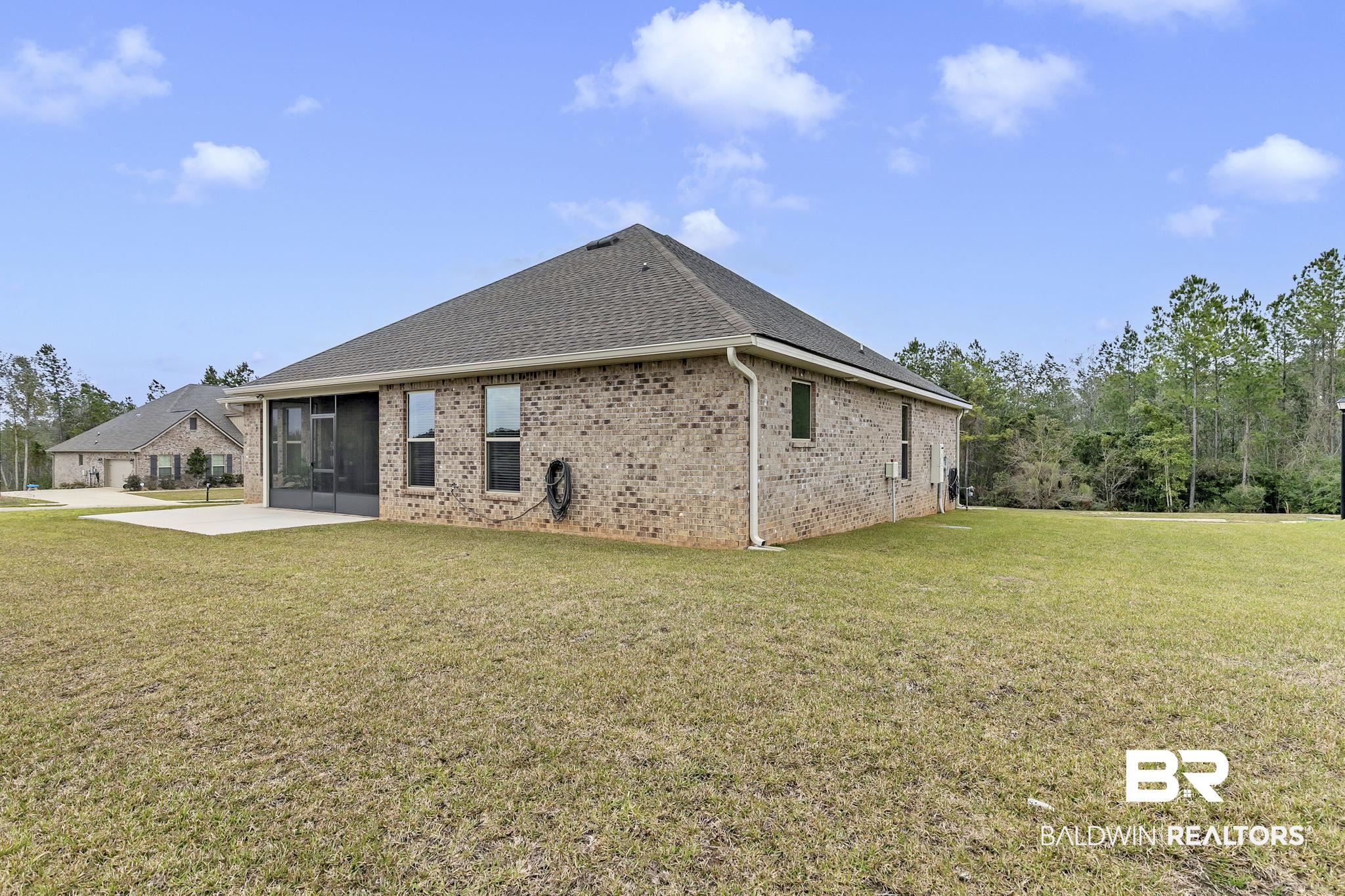 11247 Thistledown Loop Spanish Fort, AL 36527 - Photo 47 of 72 Rear view of house with a patio, brick siding, a shingled roof, a sunroom, and a lawn