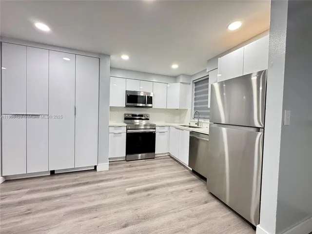 a kitchen with white cabinets and stainless steel appliances