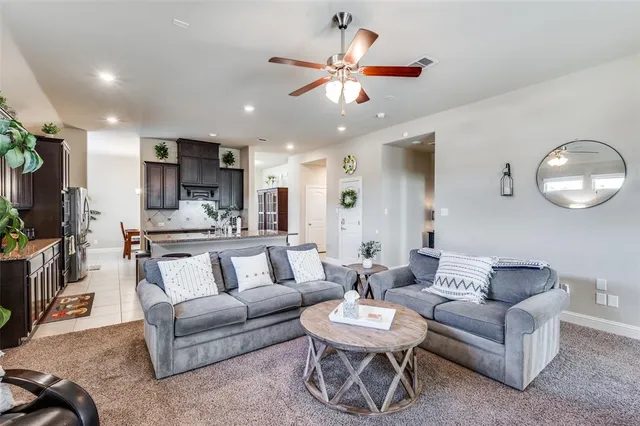 a living room with furniture kitchen view and a chandelier