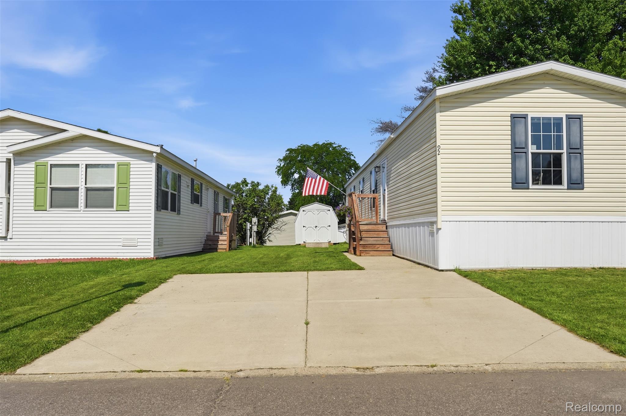 92 Normandy Drive Howell, MI 48843 - Photo 2 of 24 Exterior residential properties featuring siding, concrete driveways, and green lawns