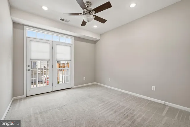 an empty room with windows and ceiling fan