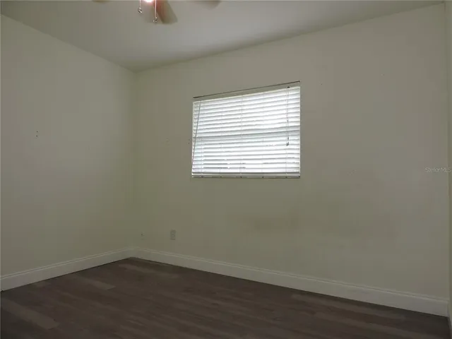 an empty room with wooden floor and a window
