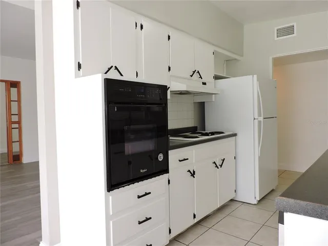 a kitchen with white cabinets and black appliances