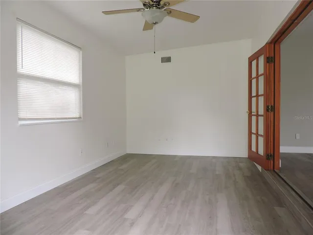 an empty room with a window and a ceiling fan