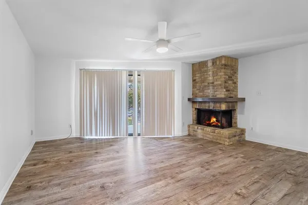 an empty room with wooden floor fireplace and windows