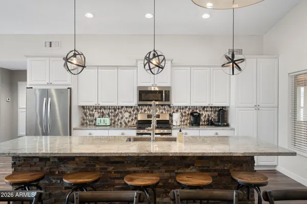 a kitchen with stainless steel appliances kitchen island granite countertop a refrigerator a sink a stove and white cabinets