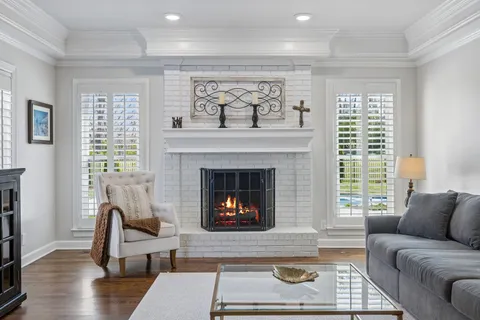 a dining room with wooden floor a chandelier a glass table and chairs