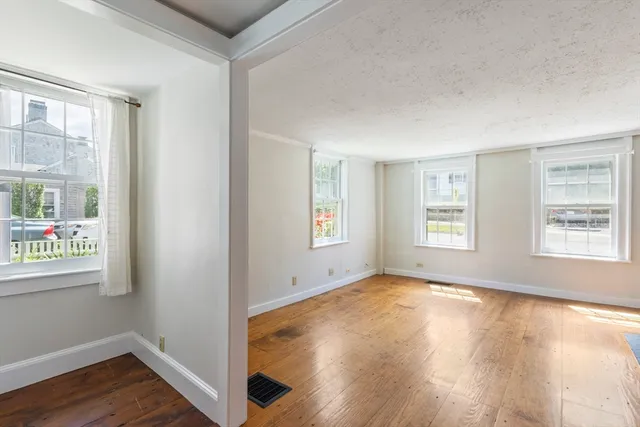 a view of an empty room with window and wooden floor