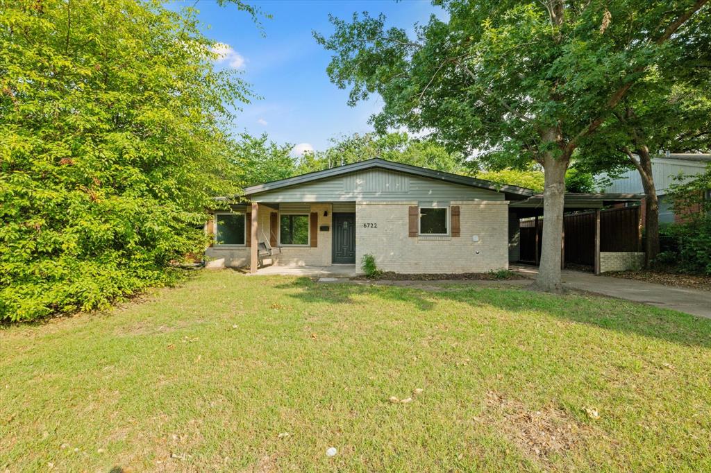 a backyard of a house with table and chairs under an umbrella