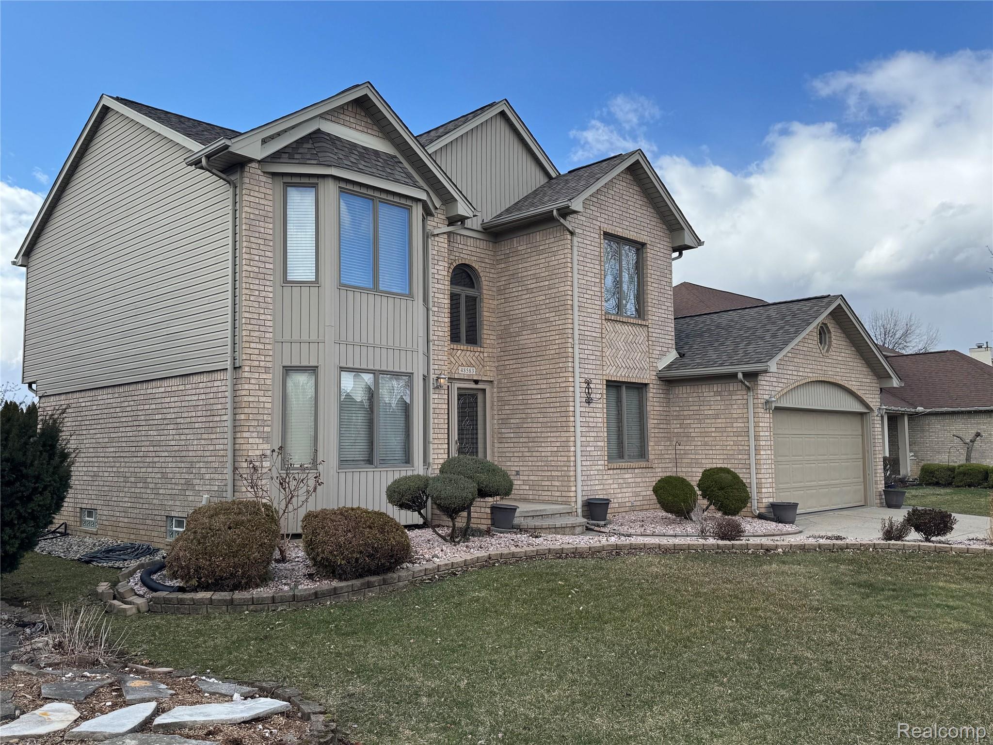 48583 Tilch Road Macomb, MI 48044 - Photo 2 of 53 View of front of home featuring a front lawn, an attached garage, roof with shingles, and brick siding