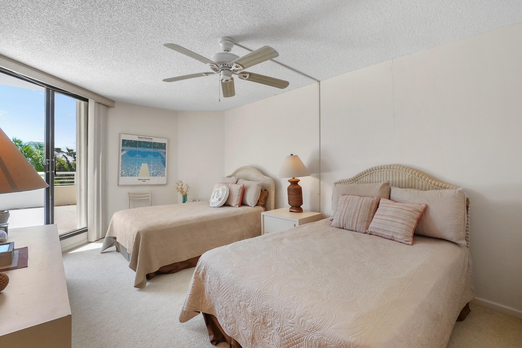 176 Helios Drive, Unit 102 Jupiter, FL 33477 - Photo 18 of 25 a bedroom with two beds and a chandelier