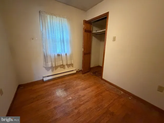 an empty room with wooden floor and closet area