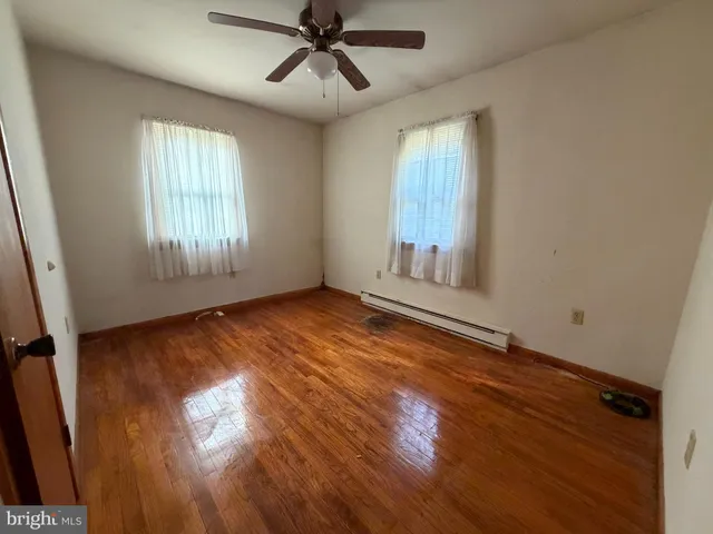 a view of empty room with wooden floor and fan