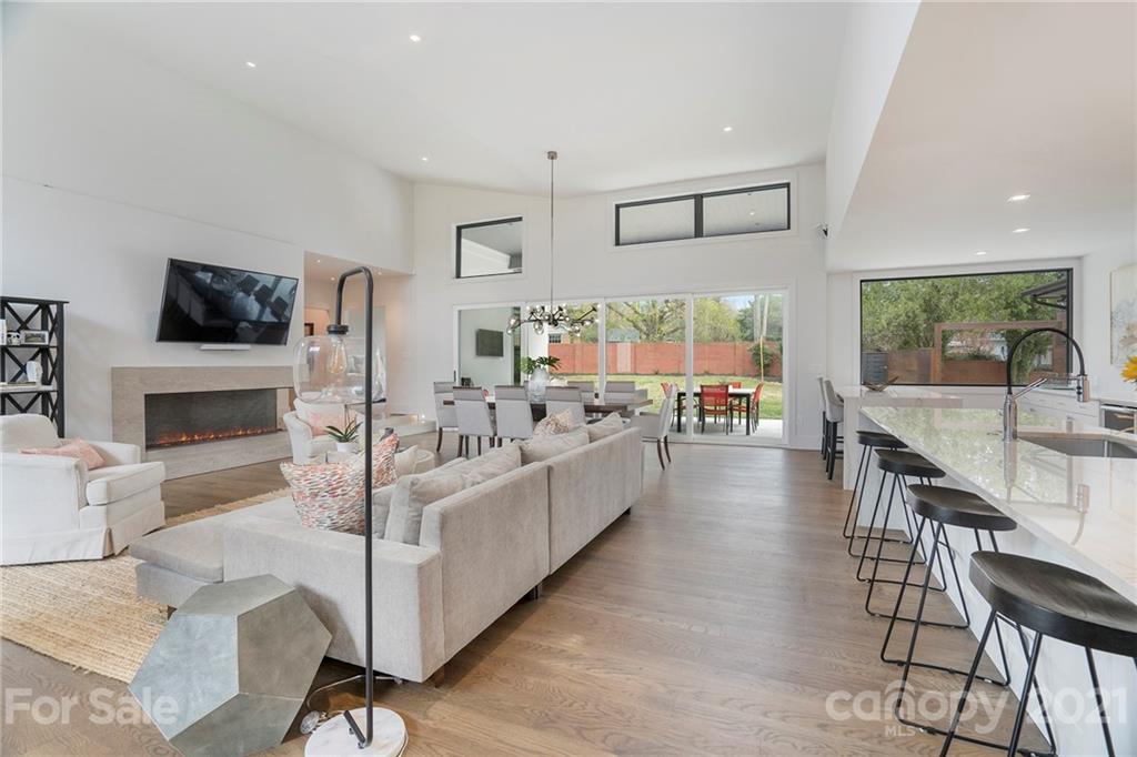 5201 Addison Drive Charlotte, NC 28211 - Photo 14 of 48 a large white kitchen with granite countertop a stove a sink a dining table and chairs with wooden floor