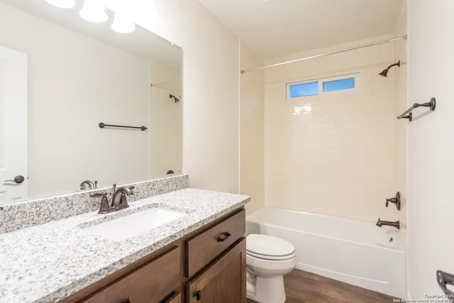 a bathroom with a granite countertop sink a toilet and shower