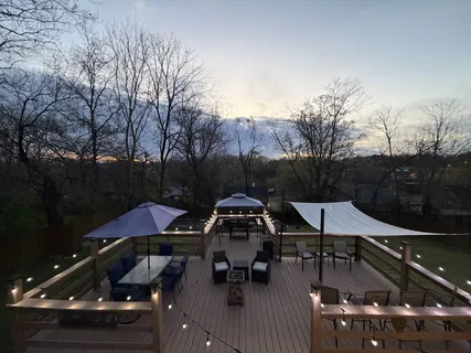 a view of a roof deck with table and chairs a barbeque with wooden floor and fence