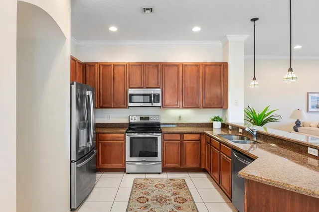 a kitchen with stainless steel appliances granite countertop a sink a stove a refrigerator cabinets and chairs