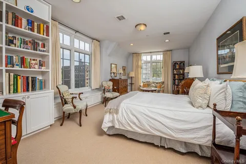 a spacious bedroom with a bed a large window and a book shelf