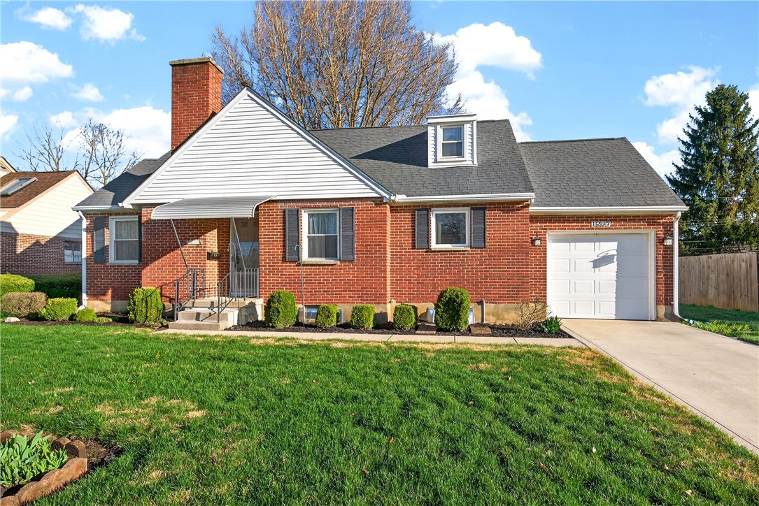 1237 Laurelwood Road Dayton, OH 45409 - Photo 2 of 56 This charming brick home features a well-maintained lawn and an attached garage.