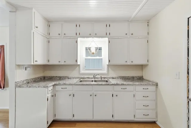 a kitchen with granite countertop white cabinets white stainless steel appliances and a sink