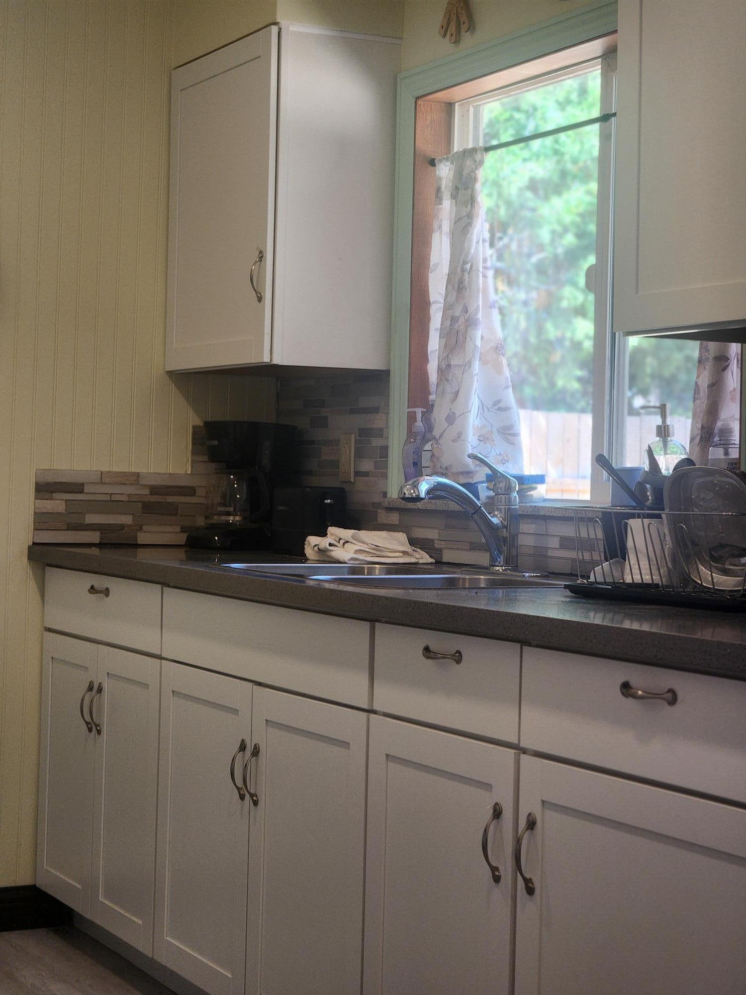 20263 Sugar Pine Street Burney, CA 96013 - Photo 7 of 22 a kitchen with windows a sink and white cabinets