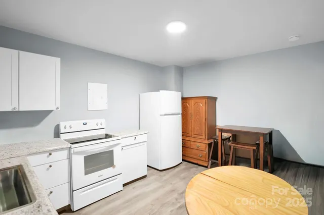 a kitchen with stainless steel appliances a stove a refrigerator and white cabinets with wooden floor