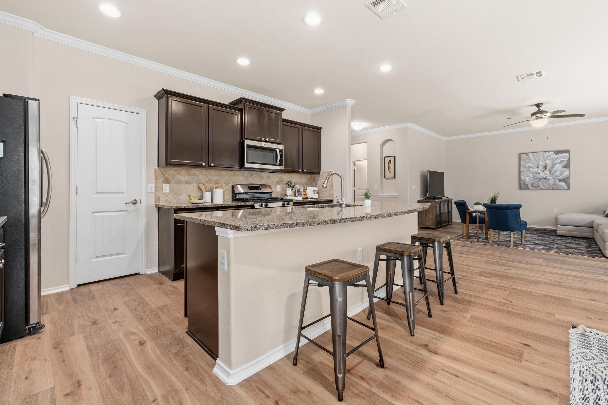 10124 Pinnacle Crest Loop Austin, TX 78747 - Photo 2 of 31 Open-concept kitchen featuring dark wood cabinetry, stainless steel appliances, and a granite-topped island with seating