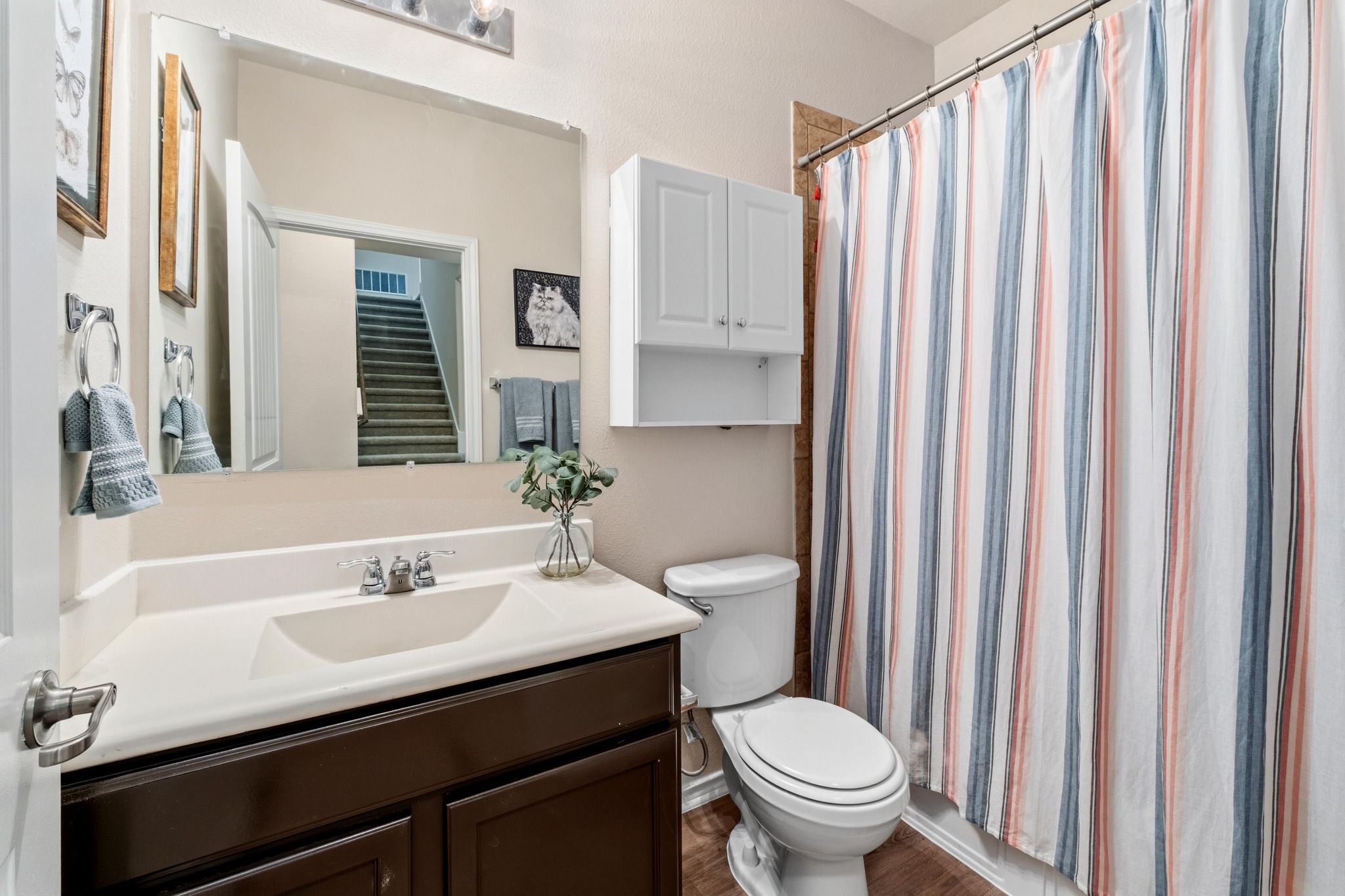10124 Pinnacle Crest Loop Austin, TX 78747 - Photo 24 of 31 Bathroom featuring a single vanity with a dark wood-finish cabinet and integrated sink, a large wall-mounted mirror, a built-in wall cabinet, and a shower with tile surround