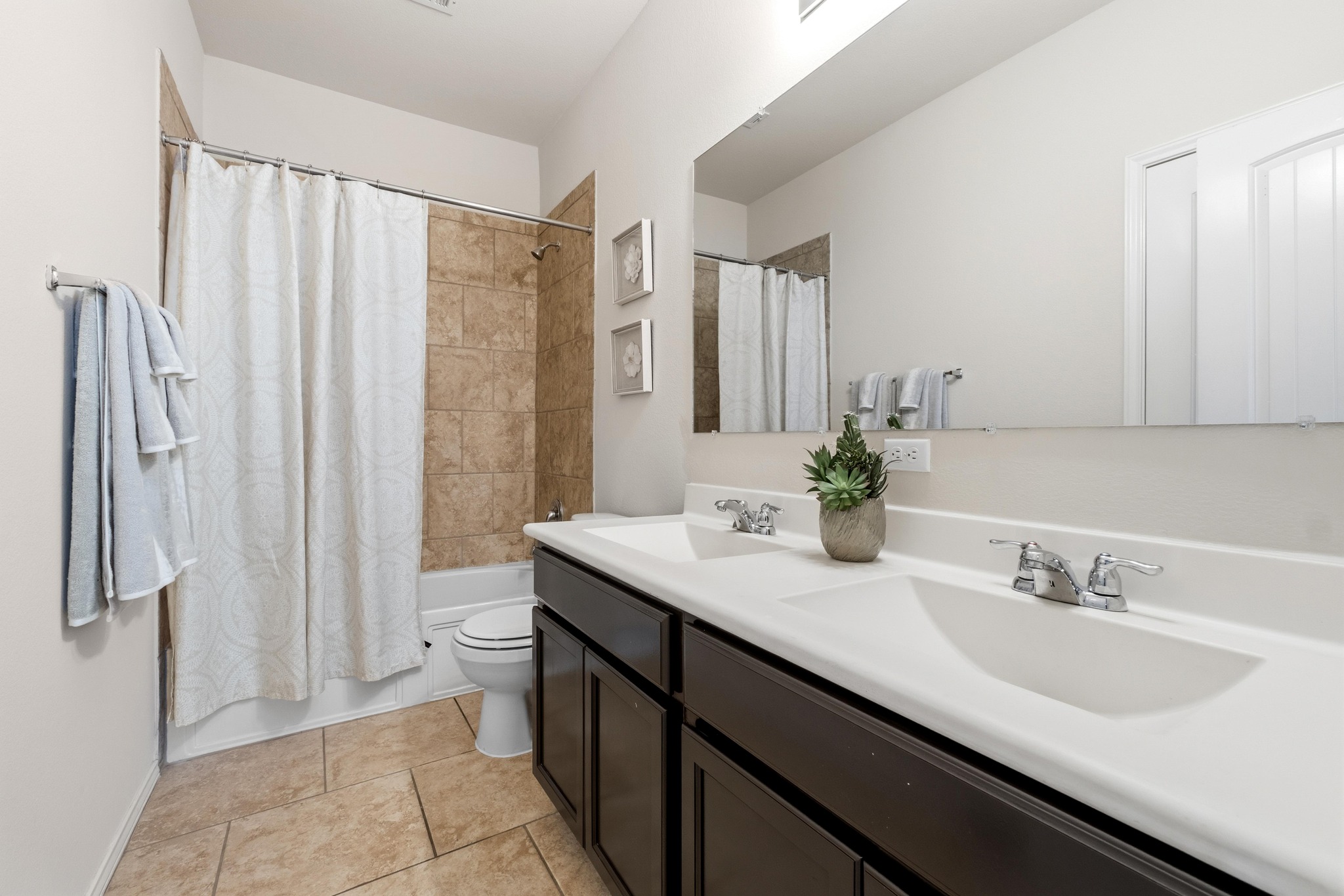 10124 Pinnacle Crest Loop Austin, TX 78747 - Photo 25 of 31 Bathroom featuring a dual vanity with integrated sinks, chrome fixtures, dark wood-finish cabinetry, a full-width mirror, and a tiled shower-bathtub combination