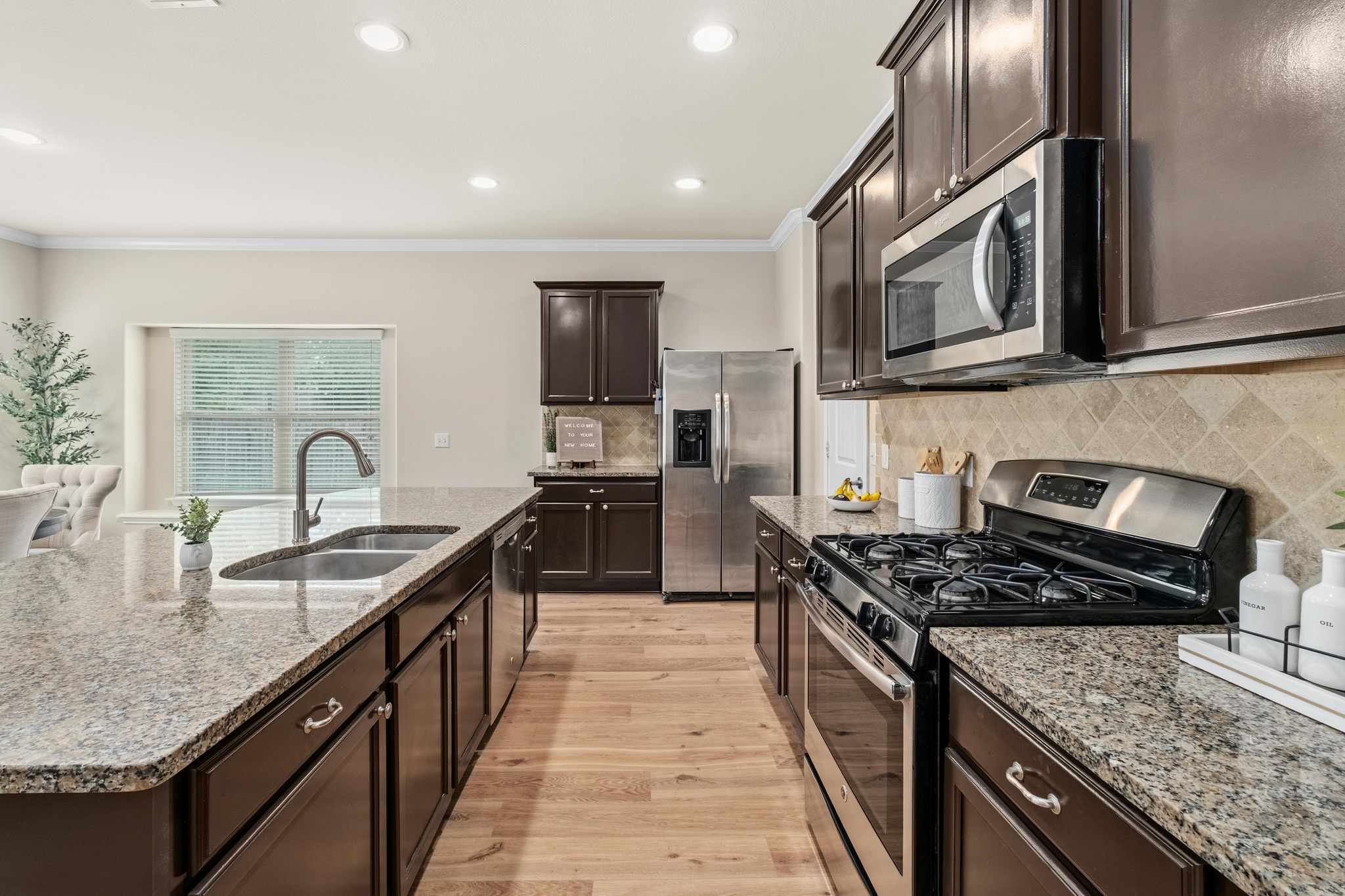 10124 Pinnacle Crest Loop Austin, TX 78747 - Photo 10 of 31 Gourmet kitchen featuring dark wood cabinetry, granite countertops, stainless steel appliances, a tiled backsplash, and wood-finish flooring