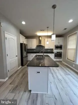 a kitchen with stainless steel appliances granite countertop a sink a stove and a wooden floors