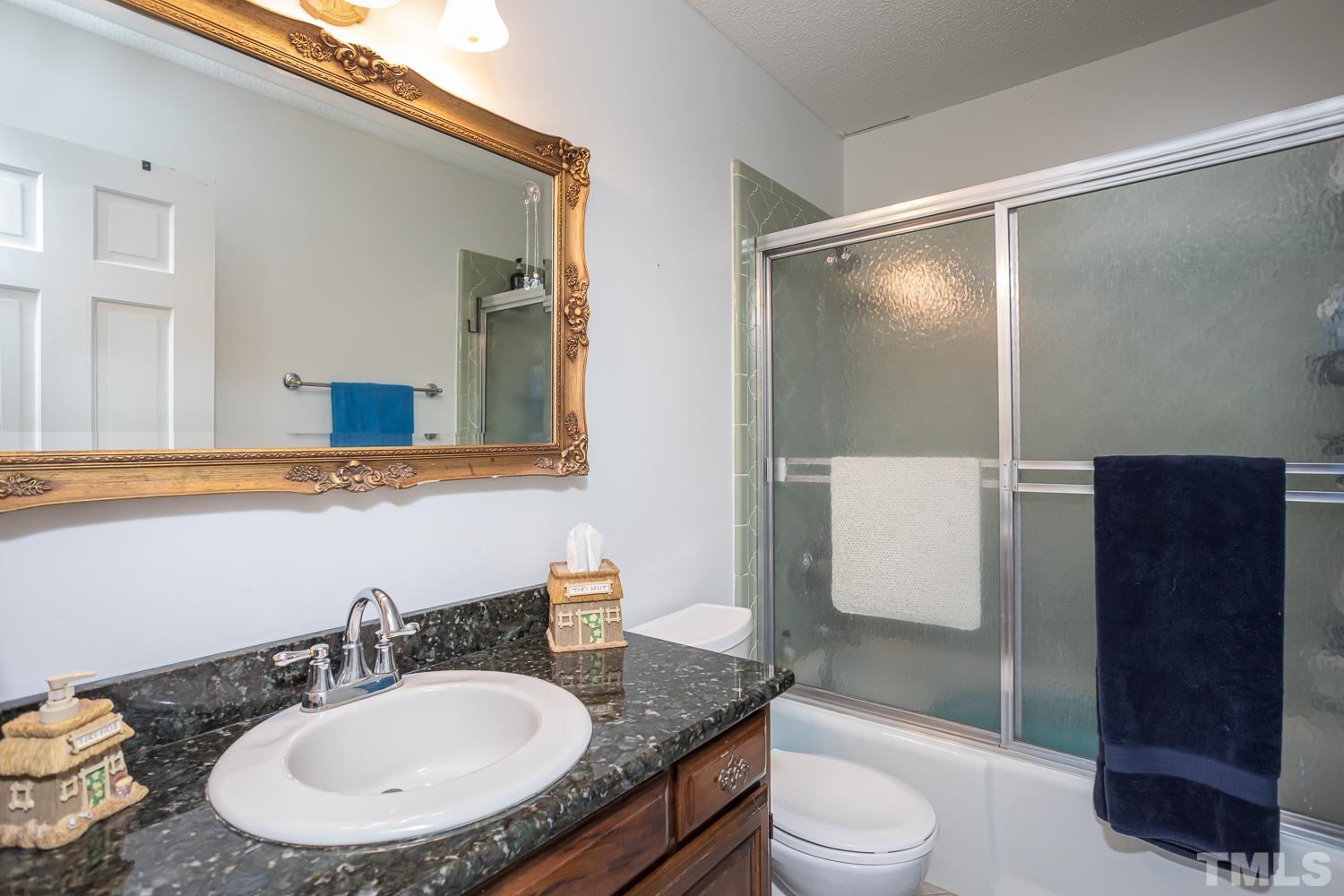 14401 Possum Track Road Raleigh, NC 27614 - Photo 16 of 30 a bathroom with a granite countertop sink toilet a mirror and shower