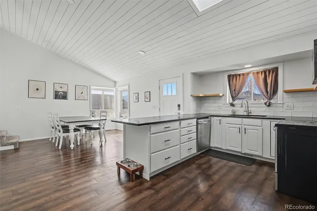 a kitchen with granite countertop a sink cabinets and wooden floor
