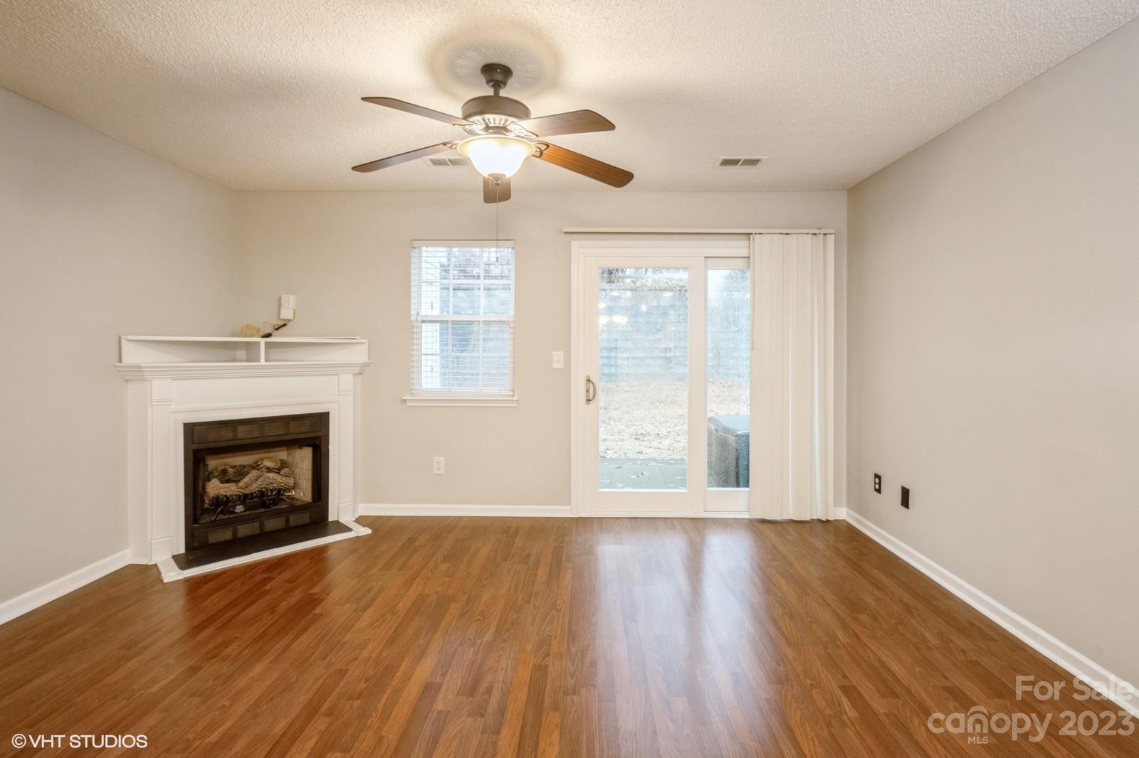 8334 Rudolph Road Charlotte, NC 28216 - Photo 8 of 31 a view of an empty room with wooden floor fireplace and a window