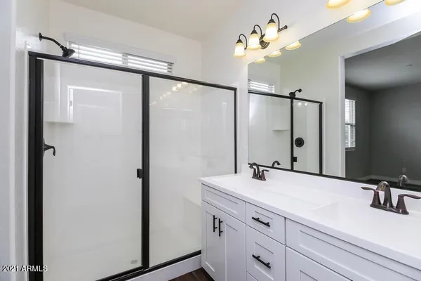 a bathroom with a double vanity sink a mirror and a shower