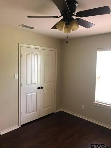 an empty room with wooden floor fan and window
