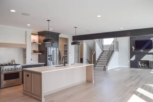 a large kitchen with stainless steel appliances a large counter top a stove and a wooden floors