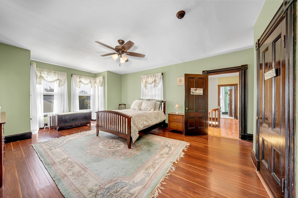 59 Washington Street Ipswich, MA 01938 - Photo 28 of 42 a spacious bedroom with a bed a couch and a chandelier