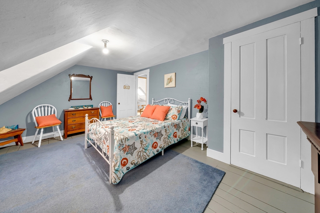 59 Washington Street Ipswich, MA 01938 - Photo 37 of 42 a bedroom with a bed and a chandelier