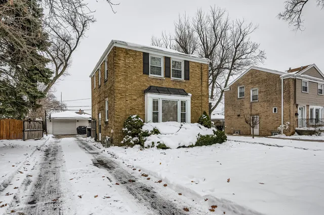 a front view of a house with a yard covered in snow