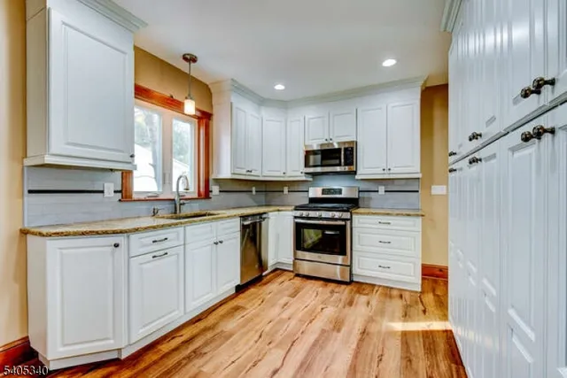 a kitchen with stainless steel appliances granite countertop a stove a sink and a refrigerator