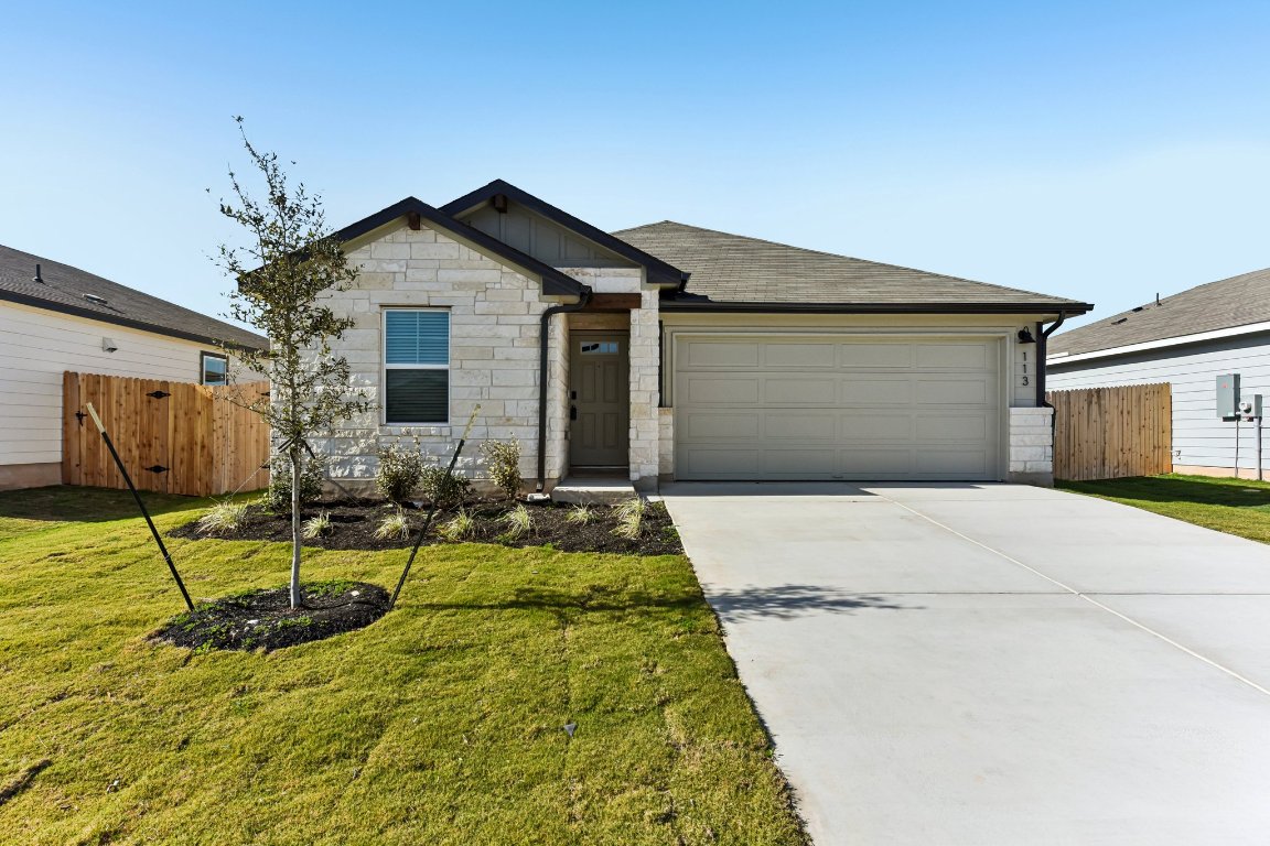 View of front of property featuring stone siding, driveway, an attached garage, and a shingled roof