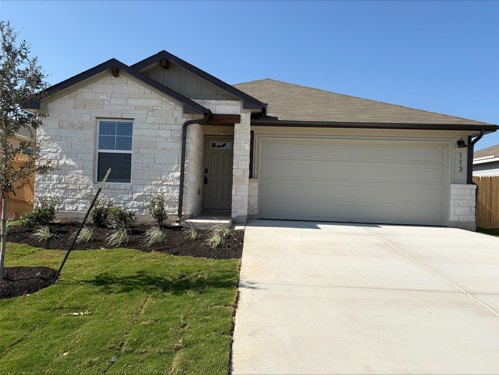 113 Honey Bee Road Jarrell, TX 76537 - Photo 5 of 10 Ranch-style home featuring stone siding, driveway, an attached garage, board and batten siding, and a front lawn
